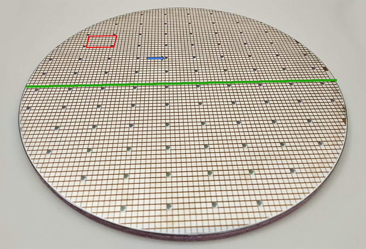 Płytka krzemowa 300 mm z tranzystorami mocy MOSFET, źródło: onsemi; zielona linia oznacza średnicę płytki, niebieska strzałka wskazuje na chip testowy a czerwony prostokąt pokazuje obszar naświetlany w czasie jednego “błysku”