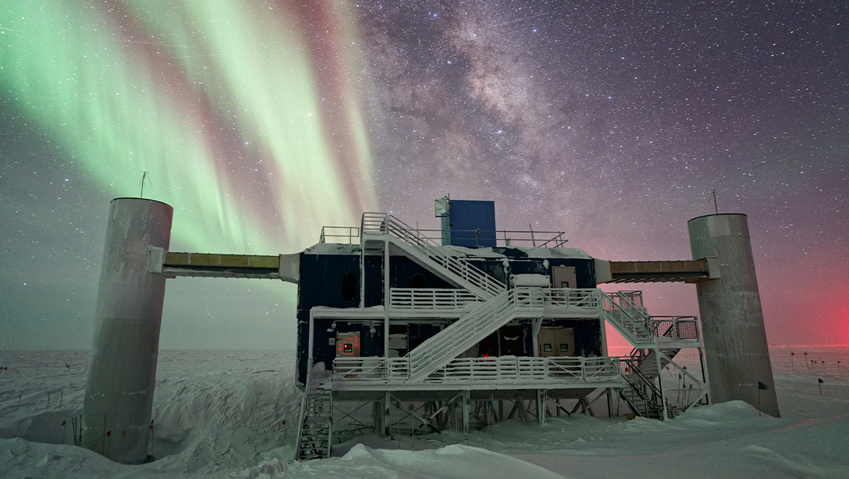 Laboratorium IceCube widziane pod rozgwieżdżonym nocnym niebem, z Drogą Mleczną widoczną w tle obok imponujących zórz polarnych | źródło: Ilya Bodo, IceCube/NSF