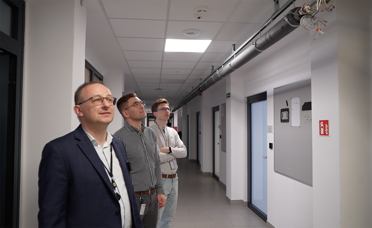Prof. Krzysztof Czuba, dr inż. Dominik Sikora i mgr inż. Andžej Šerlat na korytarzu Wydziału WETI PW, prezentujący prototyp linii referencyjnej zbudowanej dla ESS w Szwecji. Fot. Agnieszka Kubasik